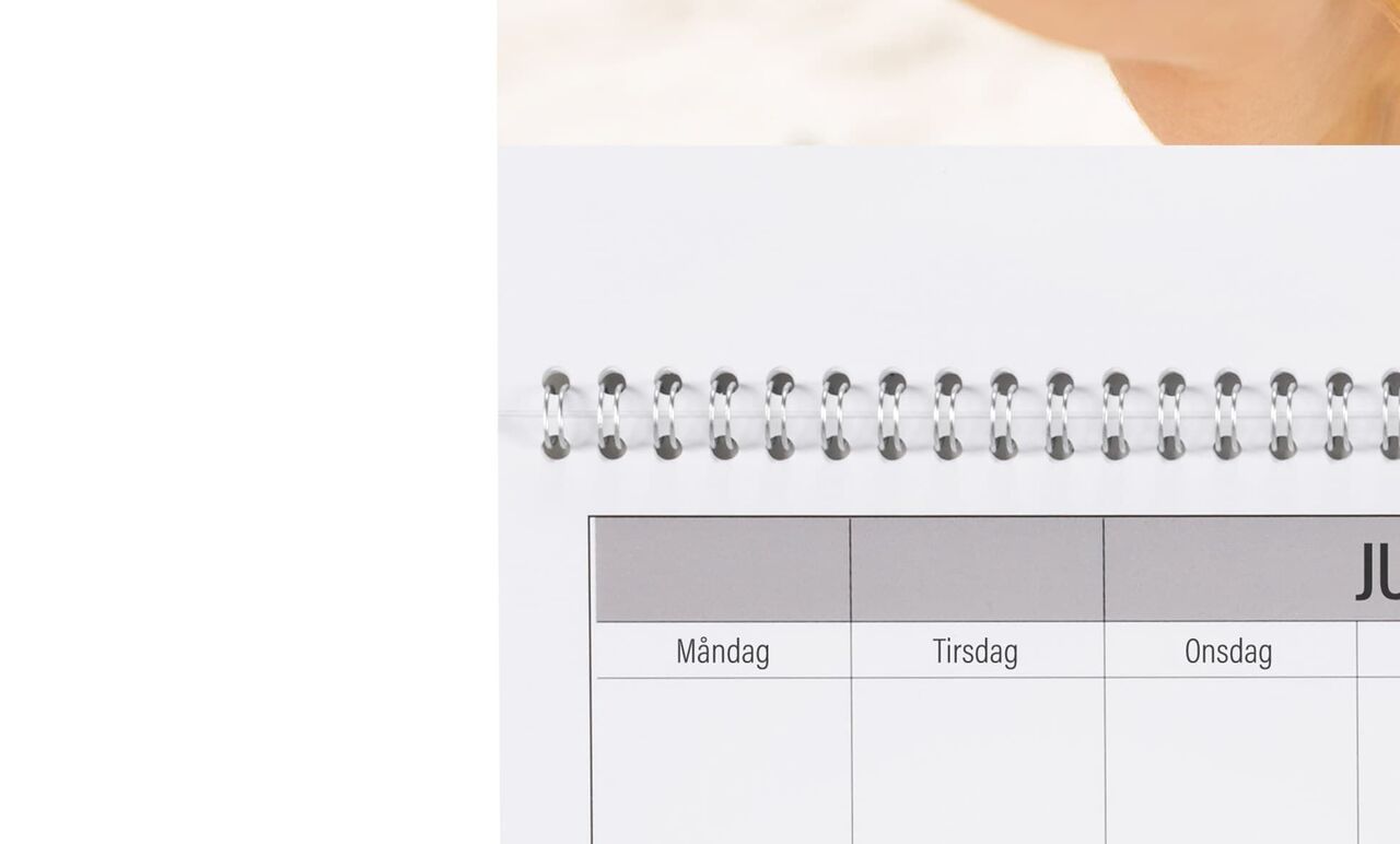 En öppen kalender med juni och en glad hand som håller en skiss.