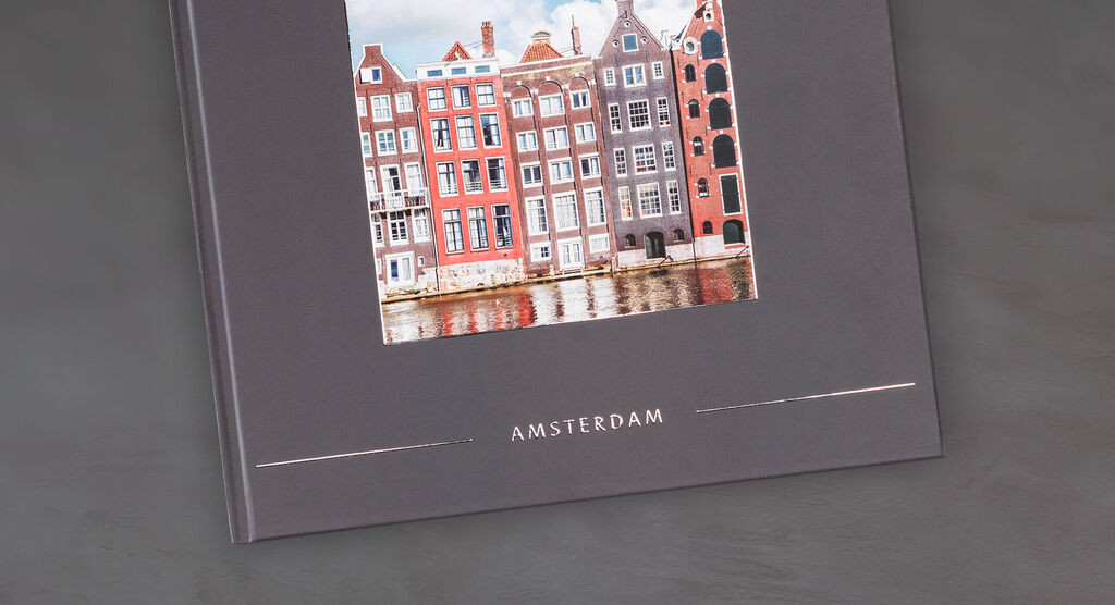 CEWE FOTOBOK med vacker bild av färgglada hus i Amsterdam på en elegant grå bakgrund.