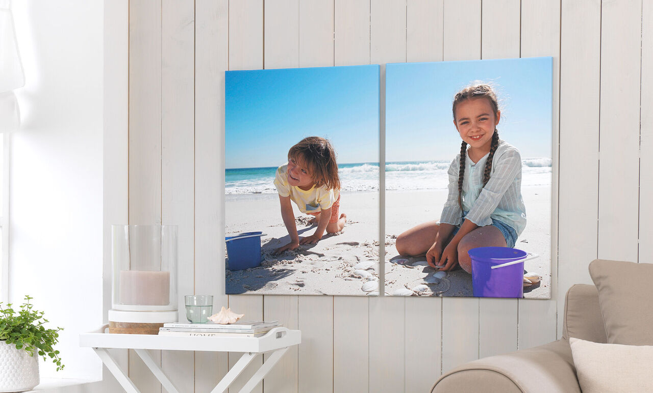 Två barn leker på stranden med sand och hinkar