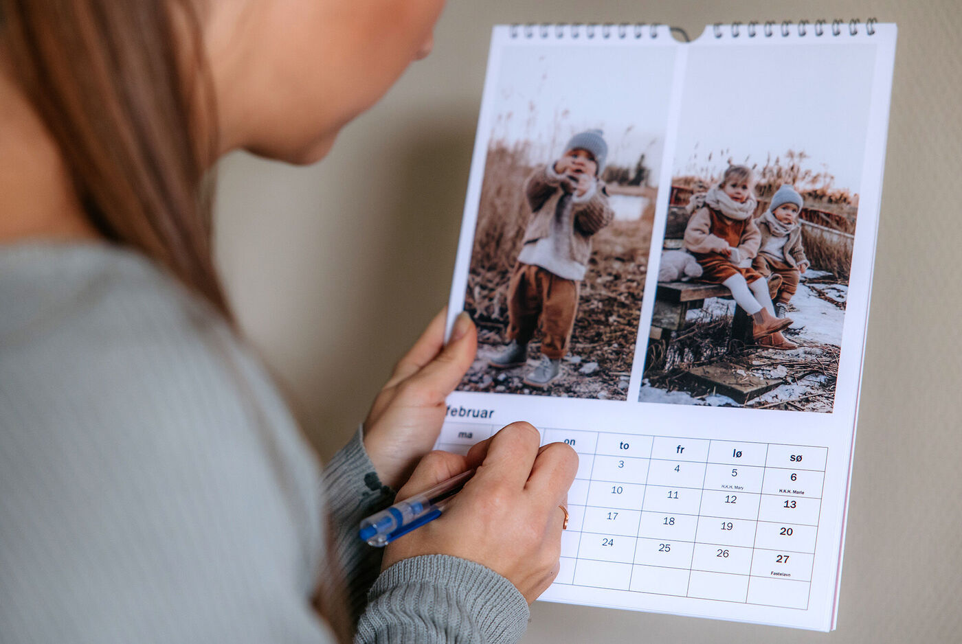 En person skriver i en fotokalender med barnbilder från vintern