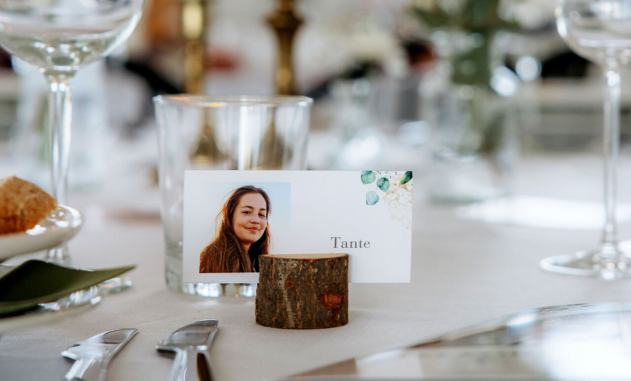 Placeringskort med namnet 'Faster' bredvid ett glas på ett festligt dukat bord.