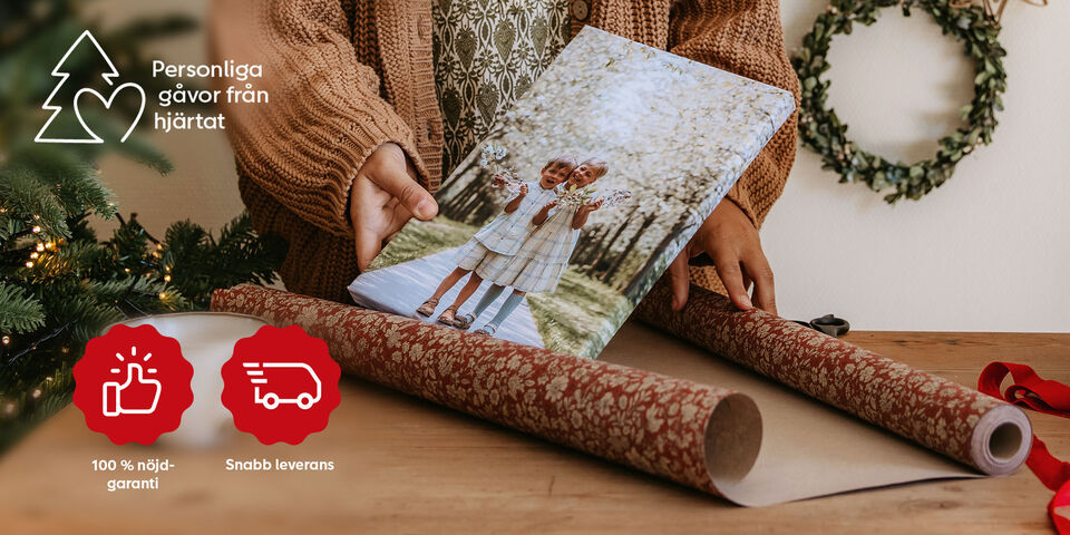 Två flickor håller en fotobok, omgivna av presentpapper och dekoration.