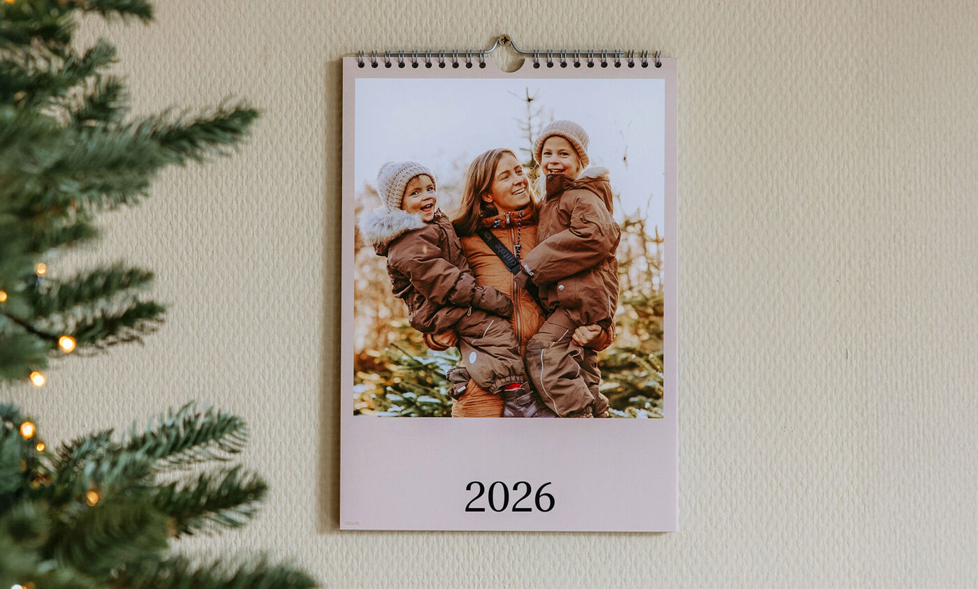 En väggkalender visar en kärleksfull familjescen med barn utomhus.