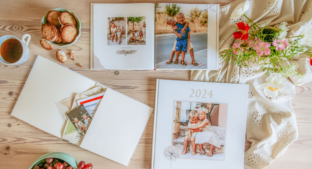 Två fotoalbum på ett bord, omgivna av snacks och blommor.