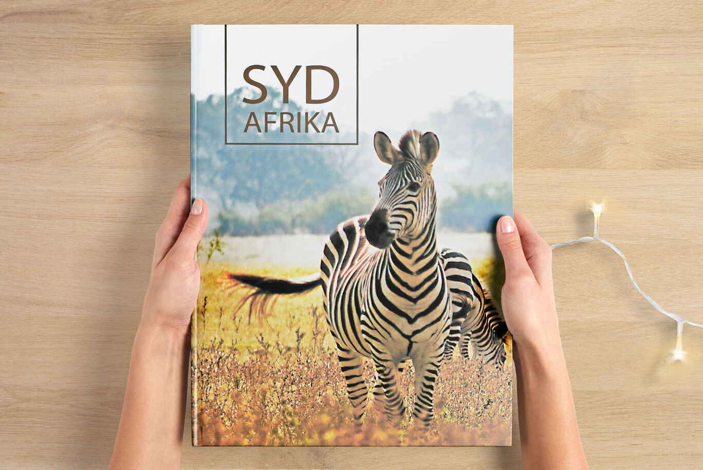 En person håller en CEWE fotobok med ett zebraomslag i händerna