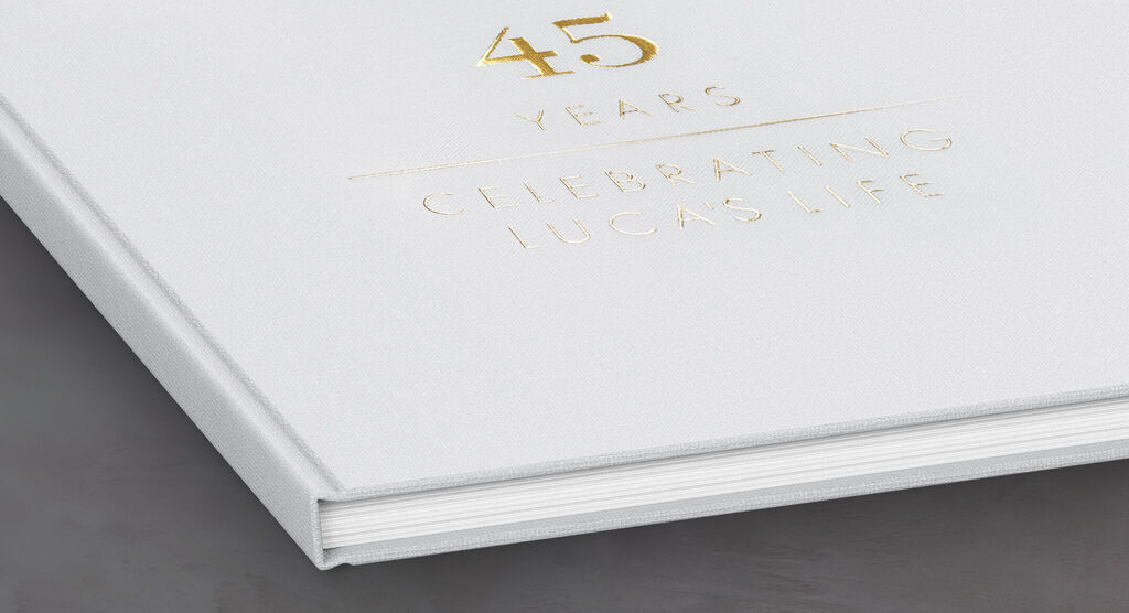 En vit fotobok med guldprägling för en 45-års födelsedag från CEWE FOTOBOK.