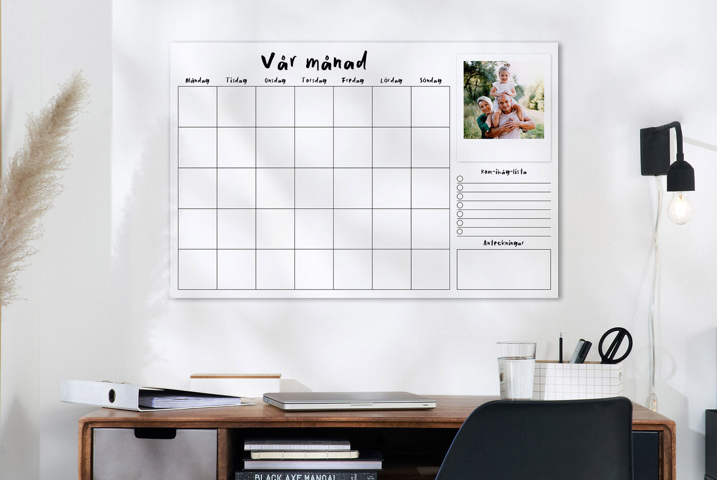 En attraktiv väggkalender med plats för personliga anteckningar, på en ljus vägg över ett skrivbord.