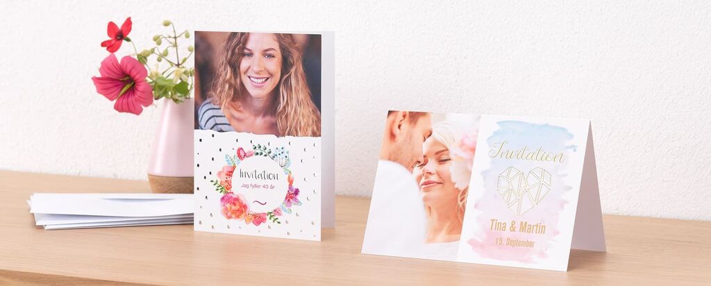 Två vackert utformade kort på ett bord, med blommor i bakgrunden