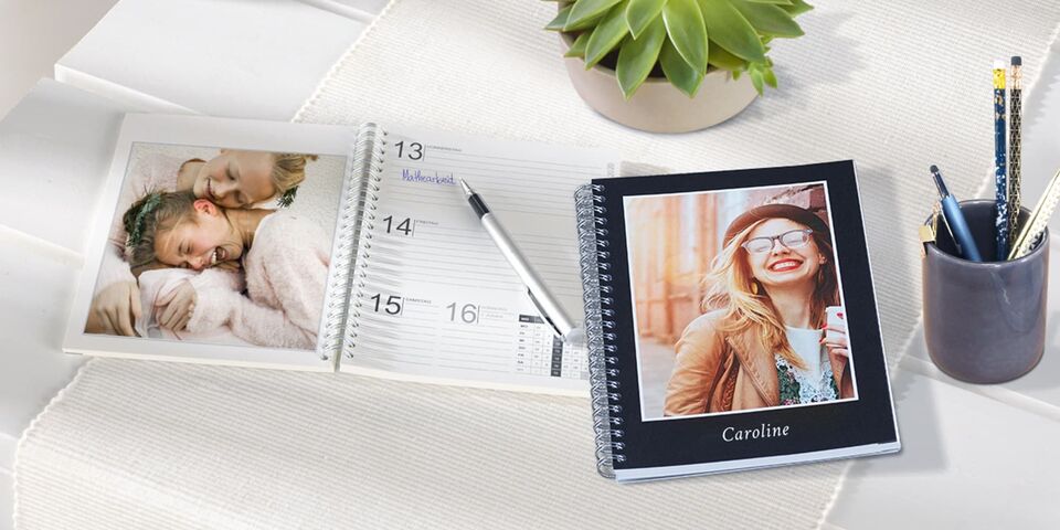En vackert designad fotokalender med personliga bilder och en minimalistisk anteckningsbok på ett bord.