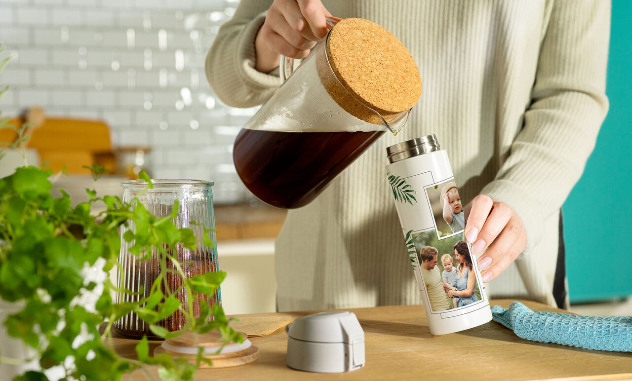 En person häller kaffe från en kanna i en personlig termosflaska med bilder.