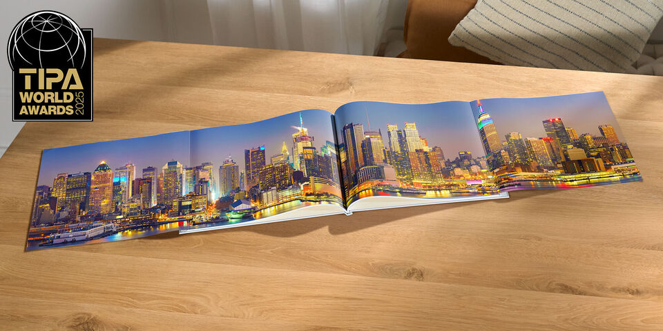 En öppen CEWE FOTOBOK på ett trädgårdsbord visar en vacker stadsbild på natten.
