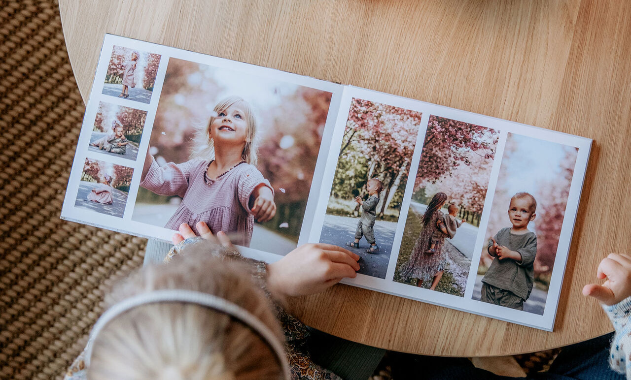 Ett barn bläddrar i en CEWE fotoalbum med familjeminnen utomhus.