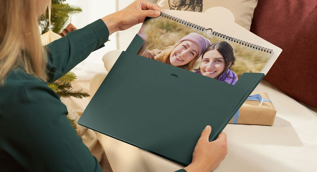 Person håller en fotokalender med bilder av lyckliga stunder
