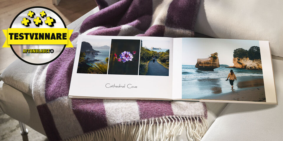 En öppen fotobok med resebilder och ett blomfoto på en mysig filt.