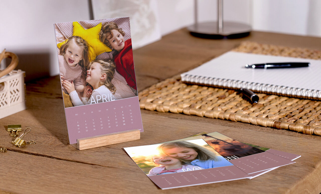 Ett färgglatt bord med CEWE fotokalender, bilder av lyckliga stunder och söta minnen.