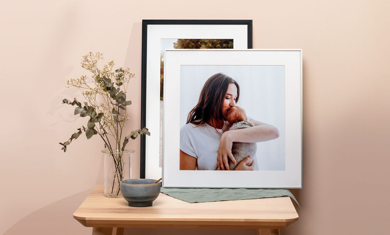 Ett inramat foto av en person med ett husdjur, dekorerat med en blomma och en skål.
