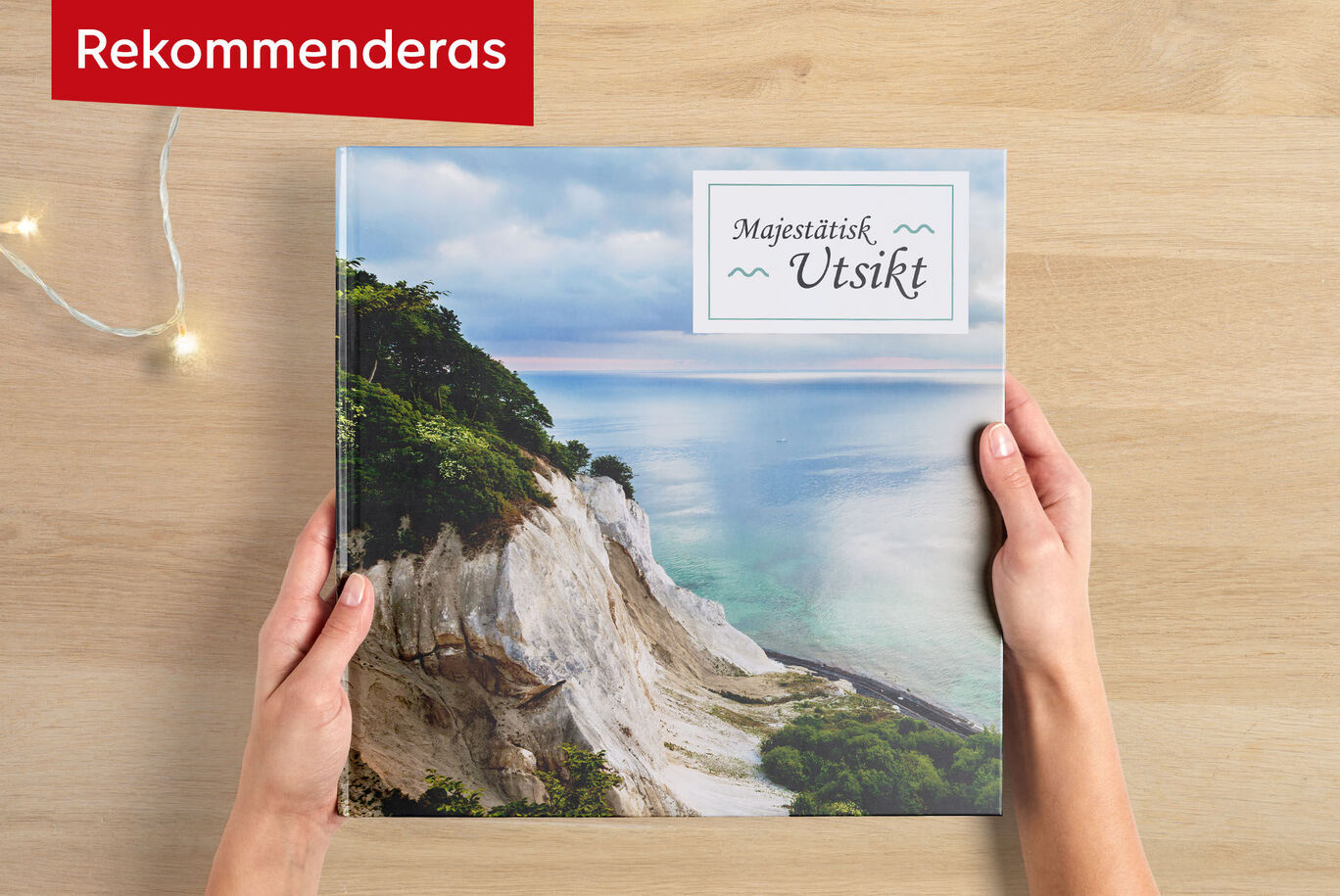 Person håller en CEWE fotobok med spektakulär landskapsbild i händerna