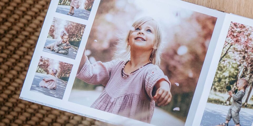En öppen fotobok visar barn i en blommande park. Ett barn njuter av blommorna omkring sig.
